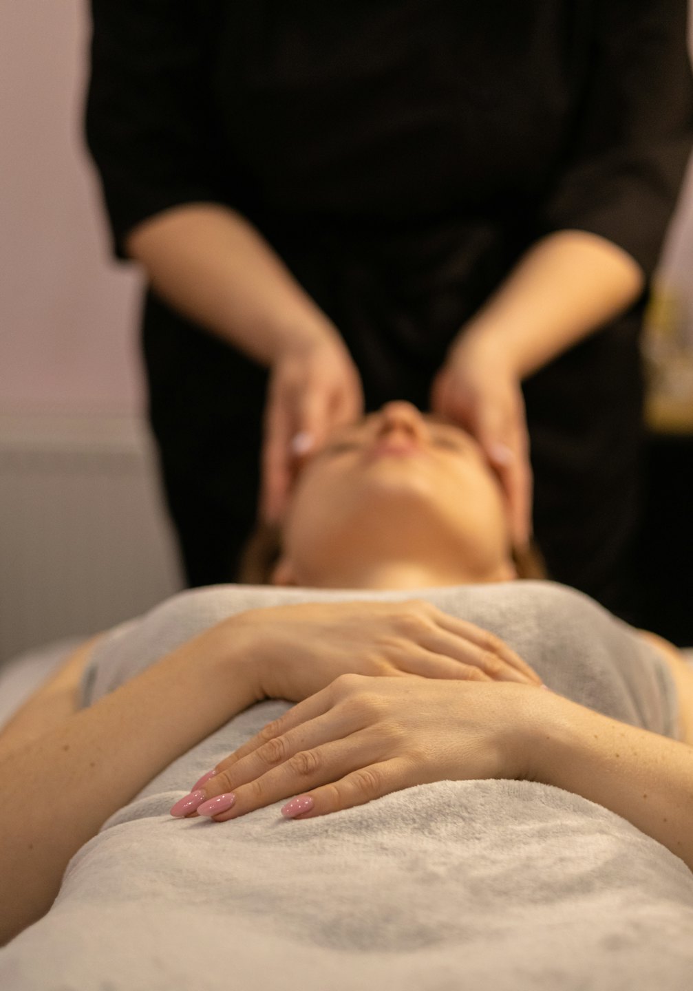 Profesjonalistka spa wykonuje masaż twarzy zrelaksowanej kobiecie.